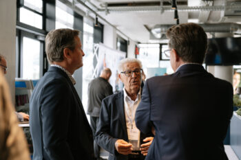 Drei Männer in Anzügen sprechen mit einander